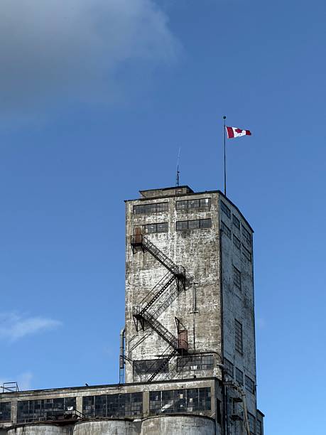 The highest part of the old Collingwood grain elevator with a Canadian flag flying on top and signs of urban decay in the building