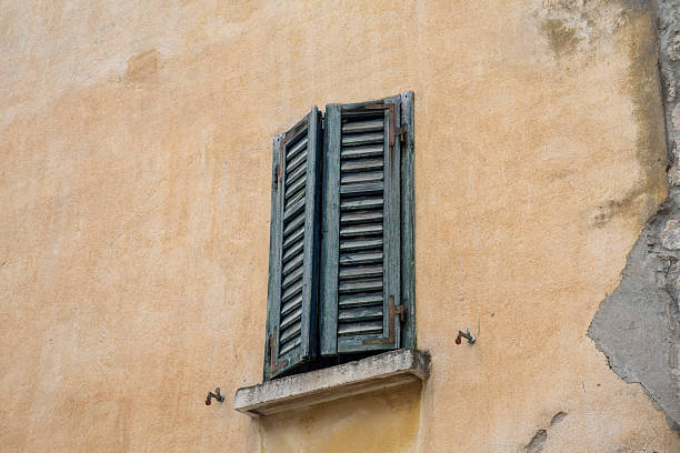 istock Weathered louvered shutters on stucco wall 2242644858