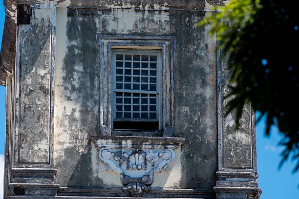 istock Weathered building with peeling paint, barred windows, and decorative motifs showing age and neglect 2242649618