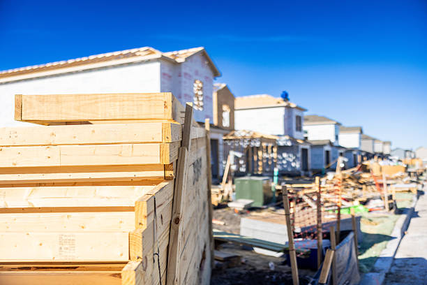 Workers are constructing beams frame of new house surrounded by trees on suburban location landscape