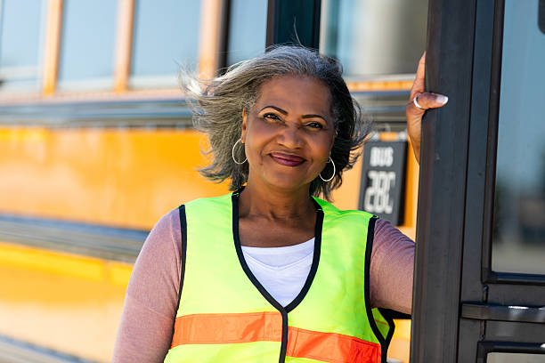 istock Woman in reflective vest smiling by a school bus, ready for her shift. 2242651947