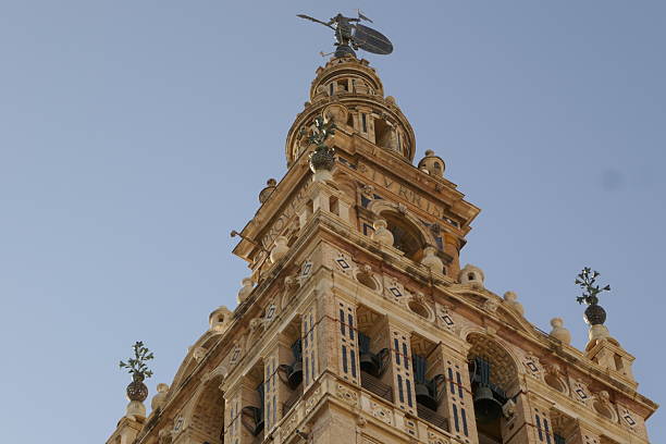 La Giralda Tower in Seville, famous landmark in Spain. Patio de Banderas with trees in the foreground.
