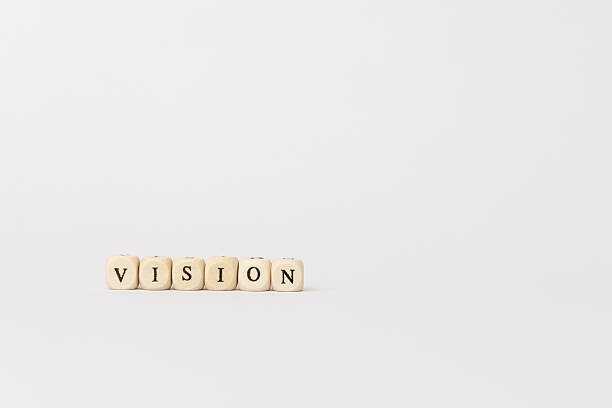 Wooden letter blocks arranged to spell vision against a clean, minimal background, symbolizing clarity and focus in growth and motivation. copy space