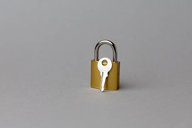 Golden padlock with a silver key positioned in front, symbolizing security and protection in finance and technology sectors. copy space