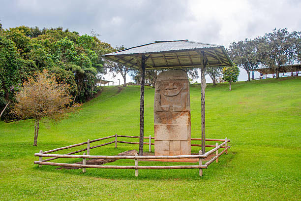 A stone statue surrounded by a protective shelter in the archaeological park of San Agustin, Colombia, showcasing pre-Columbian art.