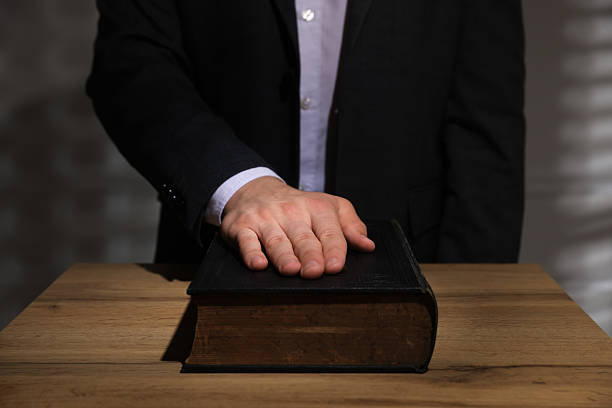 istock Man taking oath with his hand on Bible at wooden table, closeup 2242659021