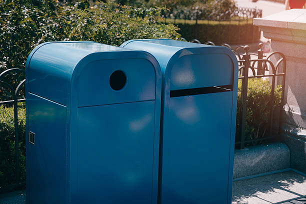 istock Vibrant Blue Trash Cans in City Park Setting Surrounded by Lush Greenery and Decorative Fencing for Urban Cleanliness 2242659694
