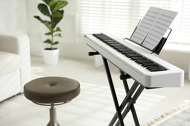 istock Synthesizer with music sheets and stool at home, closeup 2242661594