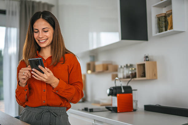 istock Happy woman using smart phone in modern kitchen 2242663780