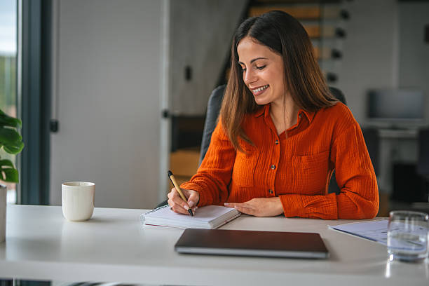 istock Woman writing notes in notebook at home office desk 2242663793