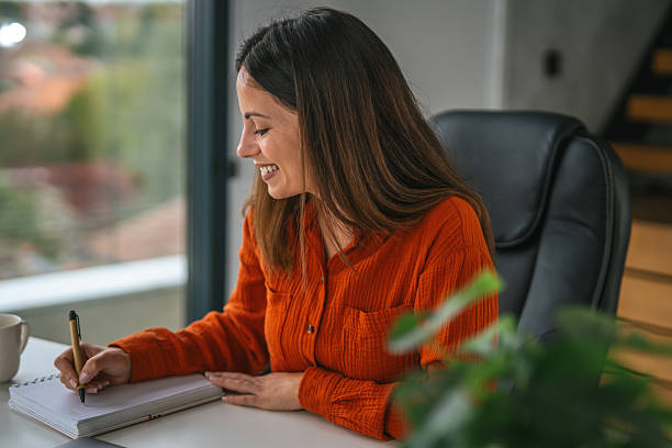 istock Woman writing notes in notebook at home office desk 2242663812