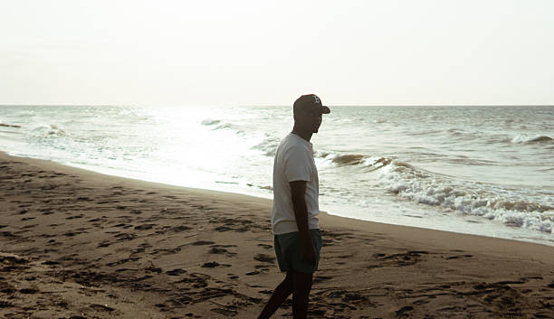 istock Young man walking on beach contemplating ocean waves at sunset 2242668004