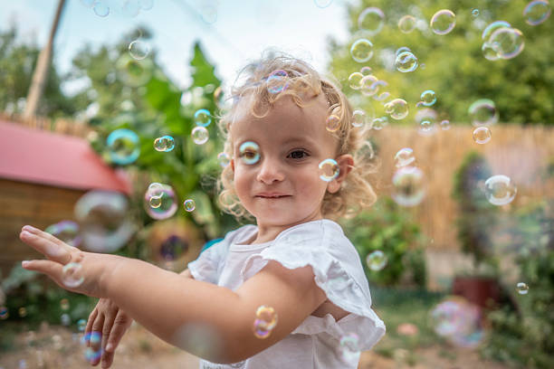 istock Joyful Child Playing with Bubbles Outdoors in a Sunny Garden Backyard 2242668177