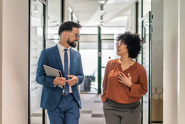 istock Business colleagues walking and conversing in office corridor 2242668241
