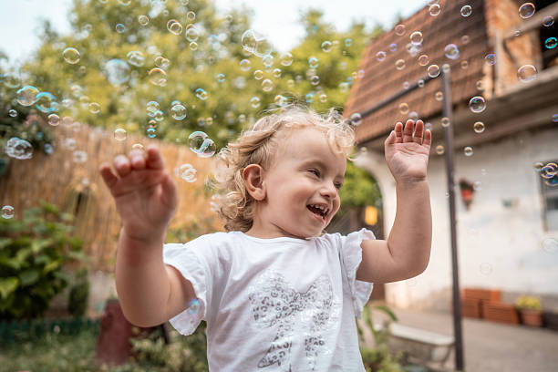 istock Joyful Child Laughing Amid Bubbles Outdoors in Sunny Backyard Playful Moment 2242668268