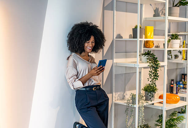 istock Black businesswoman smiling while using smartphone in office 2242668296