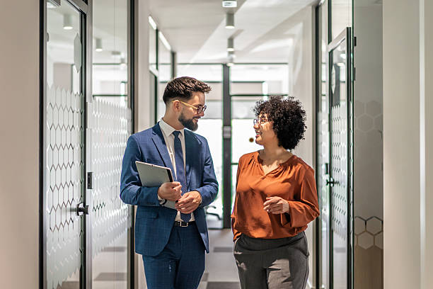 istock Business colleagues walking and conversing in office corridor 2242668445