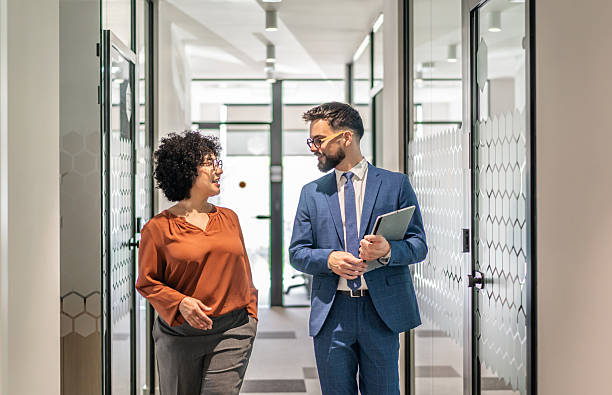 istock Business colleagues walking and talking in office hallway 2242668474