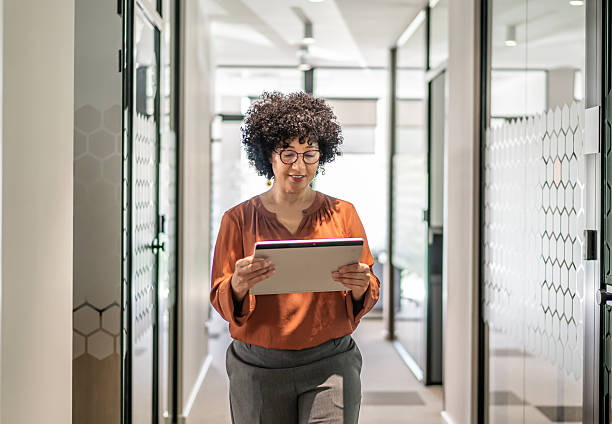 istock Businesswoman walking in office hallway using digital tablet 2242669406