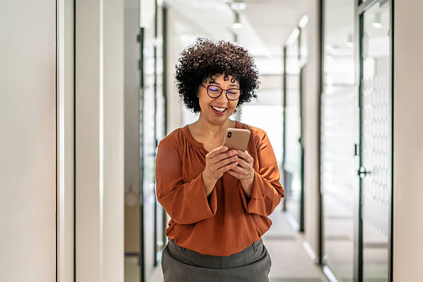 istock Mature businesswoman smiling, using phone in modern office 2242669759