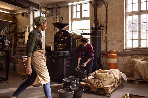 istock Coffee Roastery Team Roasting Beans, Grinding, Bagging, and Packaging in Busy Industrial Workshop Scene Today 2242674668