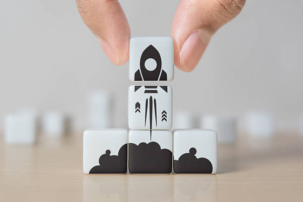 istock Business start up, start, new project or new idea concept. White dice with launching rocket graphic arranged in pyramid shape and a man is holding the top one 2242680130