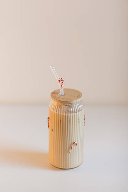 A Festive Holiday Candy Cane Glass Filled with a Peppermint Iced Latte with a Neutral Background for a Refreshing Florida Christmas