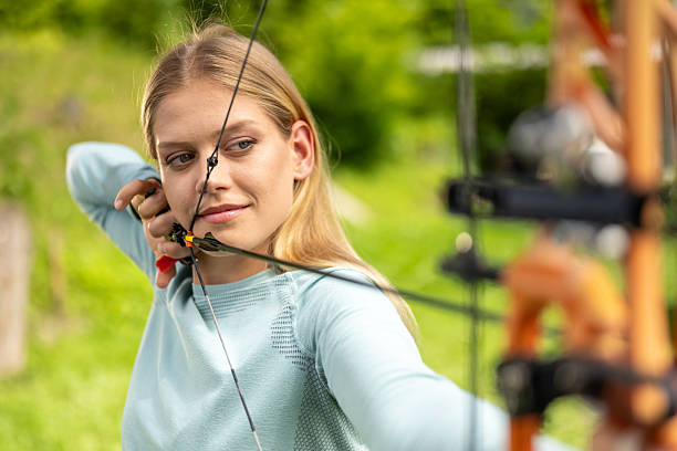 istock Caucasian Female Archer Aiming Compound Bow in Natural Setting 2242687179