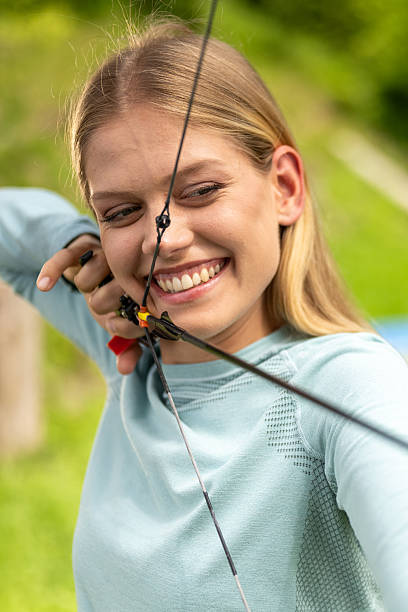 istock Young Caucasian Female Archer Smiling While Aiming Bow Outdoors 2242687182