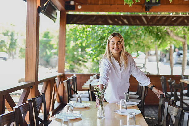 Portrait of a young female server holding a serving tray while standing in a restaurant indoors.