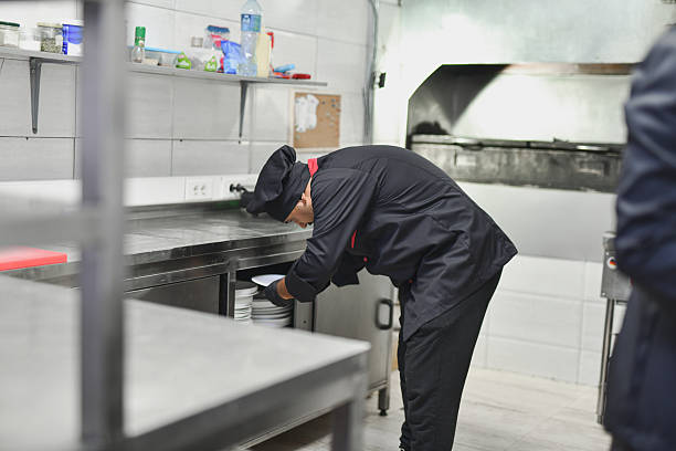 Professional Chef Preparing Plates in a Busy Kitchen Scene at a Stainless Steel Counter