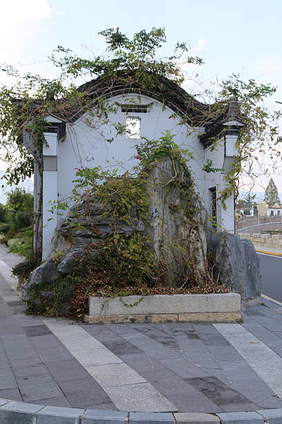istock the small white building on the roadside is covered with vines and plants, surrounded by gray stone walls. 2242697205