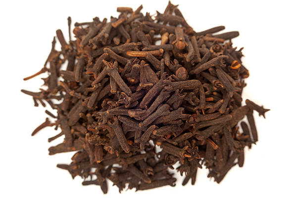 Horizontal photo of cooking cloves grouped in the center on a white background. The image highlights the texture, shape, and natural color of the cloves with sharp focus and fine detail