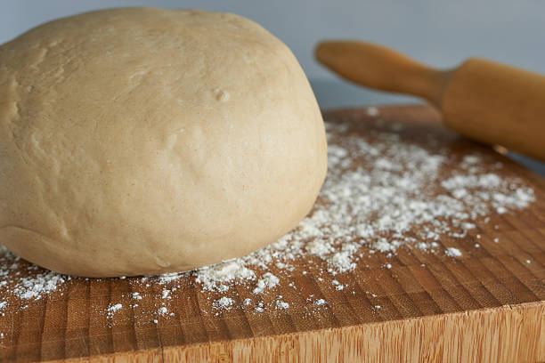 istock Bread dough and rolling pin on a wooden board with flour. 2242705385