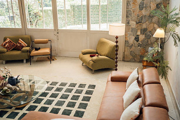 Retro charm meets modern style in this living room with vintage armchairs, a glass coffee table, and a bold patterned carpet.