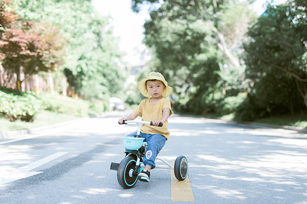 Cute Child in Sun Hat on Tricycle in Outdoor Setting