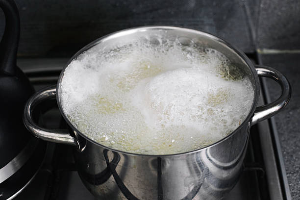 Boiling pot with water foam overflowing on stove. Kitchen problem of boiling over and cleaning after cooking.