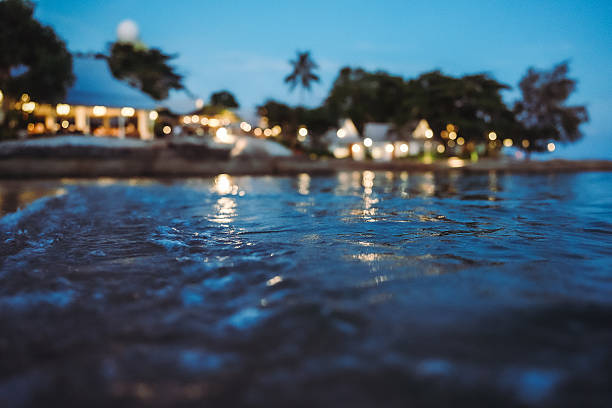 Peaceful seaside resort illuminated by warm bokeh lights at twilight with gentle ocean waves and tropical atmosphere, creating a relaxing beach vacation mood in Thailand.