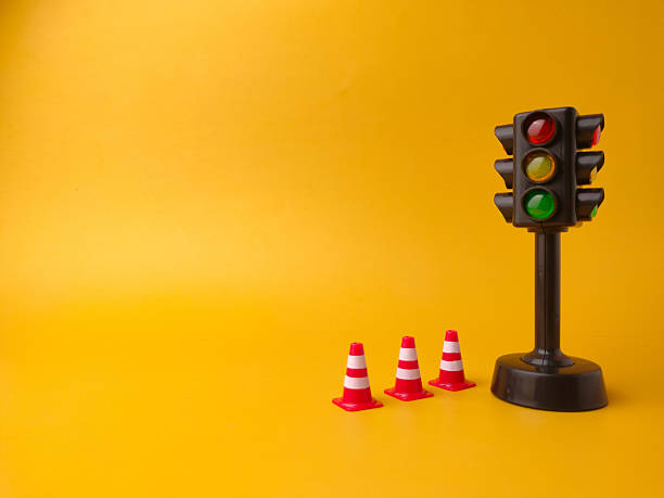 istock The image shows a miniature traffic light and three miniature traffic cones on a yellow background 2242715528