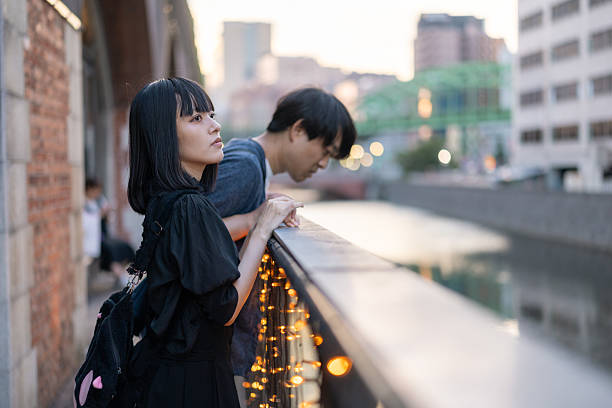 Couple looking at view from riverside at sunset time