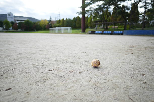 man measuring the distance between metallic petanque balls and a small red jack on fine gravel