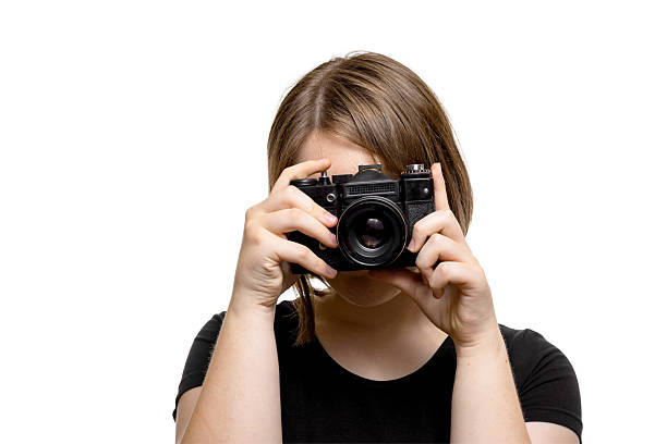 Young woman in black t-shirt taking a picture with camera, isolated on white background.