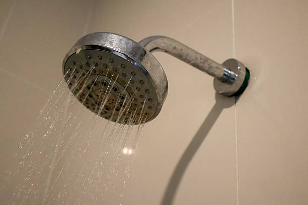 istock Close-up of a chrome shower head attached to a tiled wall 2242723007