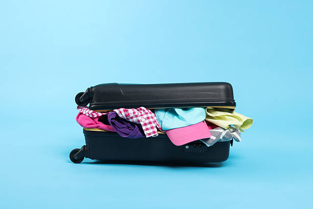 istock Packed suitcase full of clothes on light blue background 2242725286