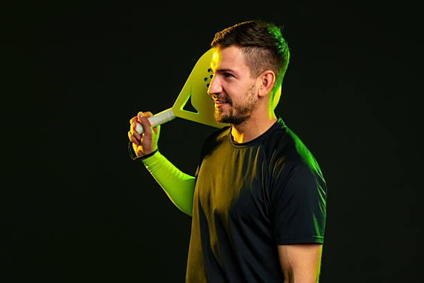 istock Man holds paddle and smiles in studio with dark background during sport practice session 2242727124
