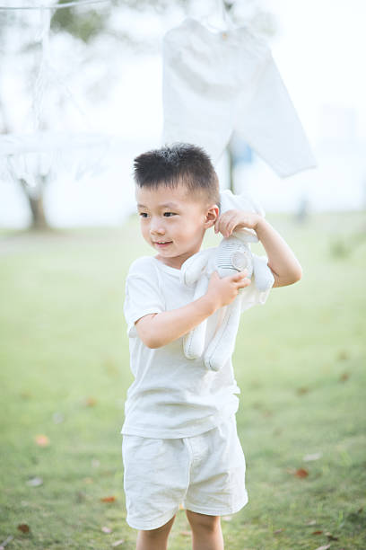 Cute Boy Playing with Stuffed Bunny Toy on Grass