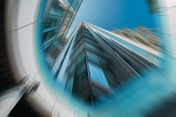 An abstract image of Hong Kong architectures is shown with a dynamic radial blur effect, focusing on modern glass and steel buildings. A vibrant blue sky peeks through.