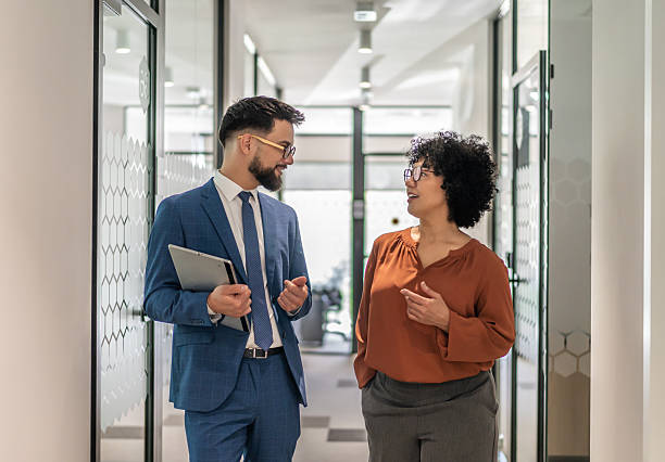 istock Business colleagues walking and talking in office hallway 2242747304
