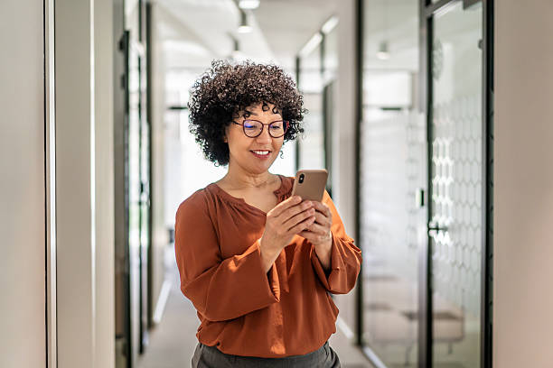 istock Businesswoman using smartphone in office hallway 2242748031