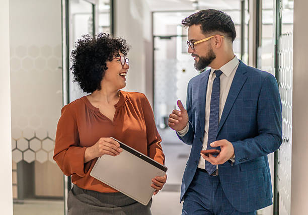 istock Diverse business professionals talking and smiling in office hallway 2242748344